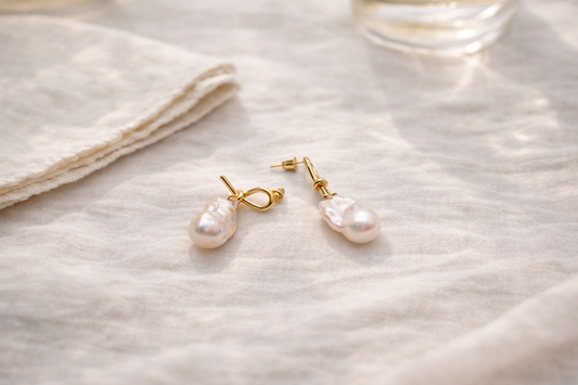 Baroque pearl guide editorial flat lay with baroque pearl earrings and necklace on soft linen